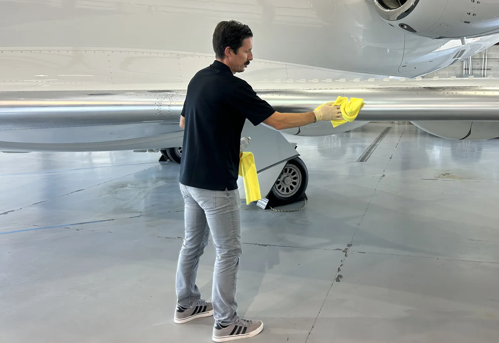 Technician cleaning the leading edge of a private aircraft inside a hangar